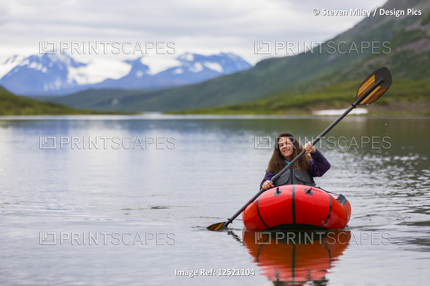 A woman paddles a packraft across Landmark Gap Lake, off the Denali highway, ...