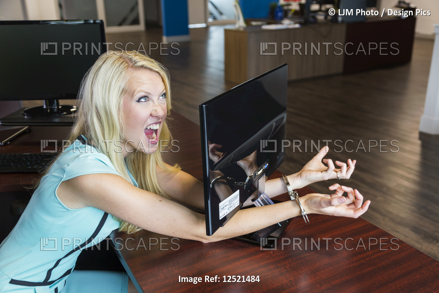 Young millennial business woman handcuffed to her computer monitor in the ...