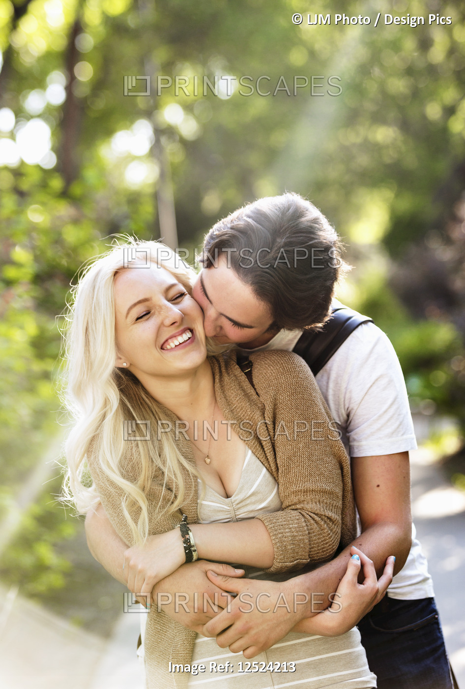 A young couple shares a romantic moment together in an embrace on a pathway on ...