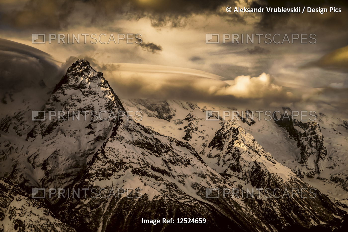 Dramatic view of snow-covered Caucasus Mountains and glowing clouds, Dombay ...