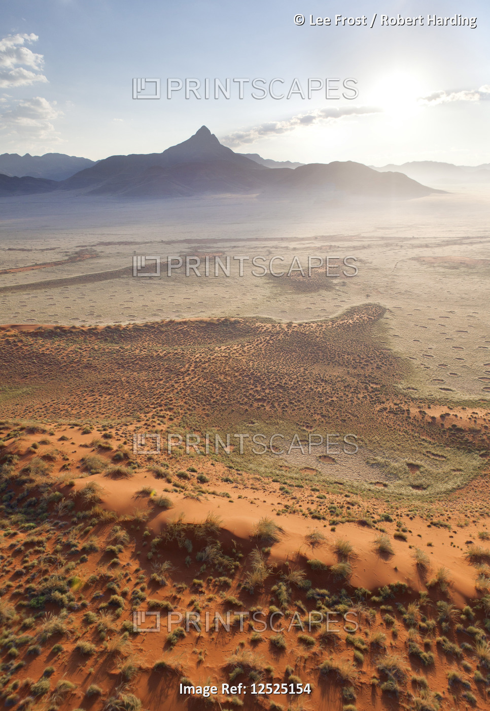 Aerial view from hot air balloon at dawn over magnificent desert landscape of sand dunes, mountains 