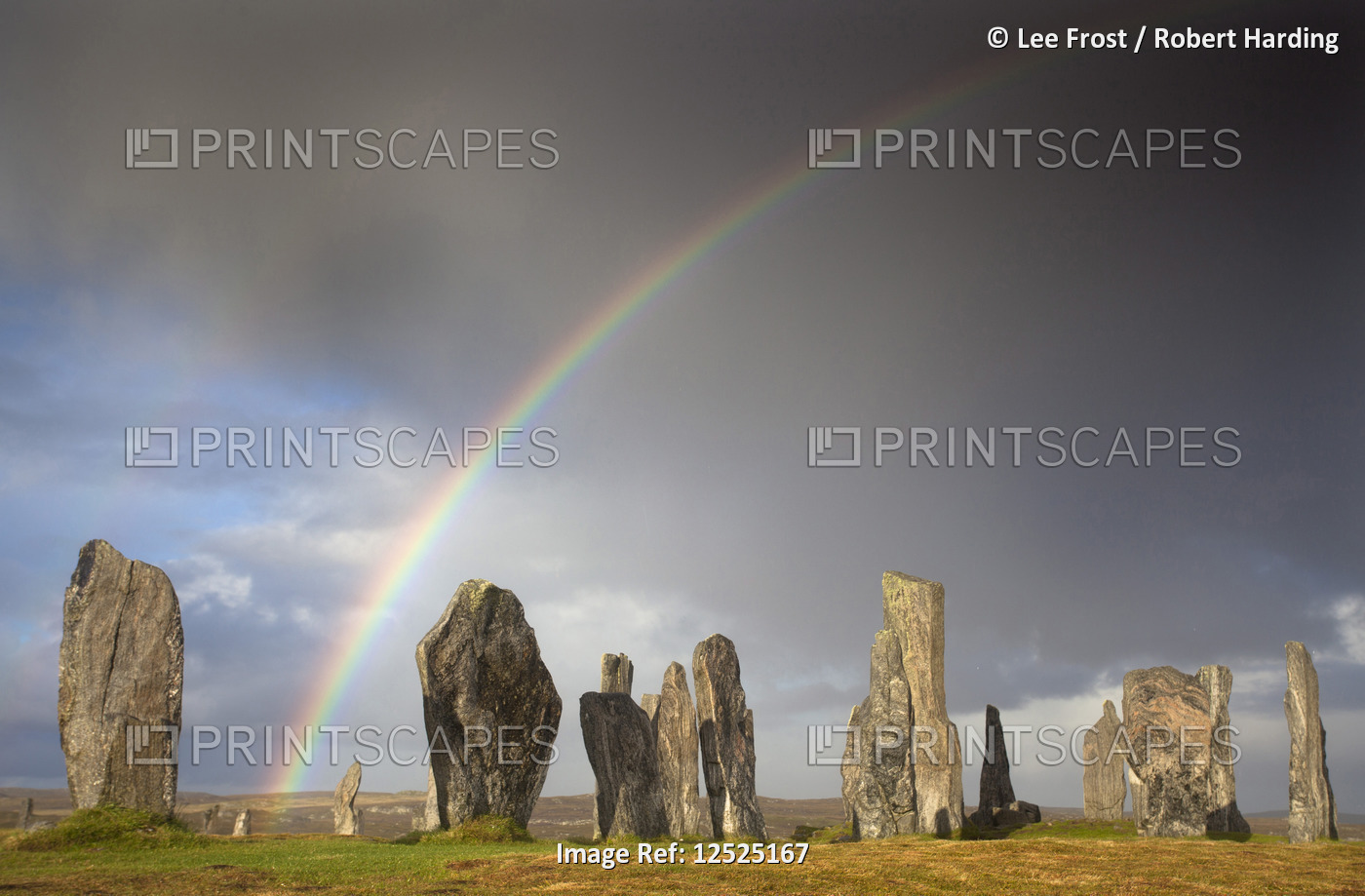 Standing Stones of Callanish bathed in sunlight with a rainbow arching across the sky in the backgro