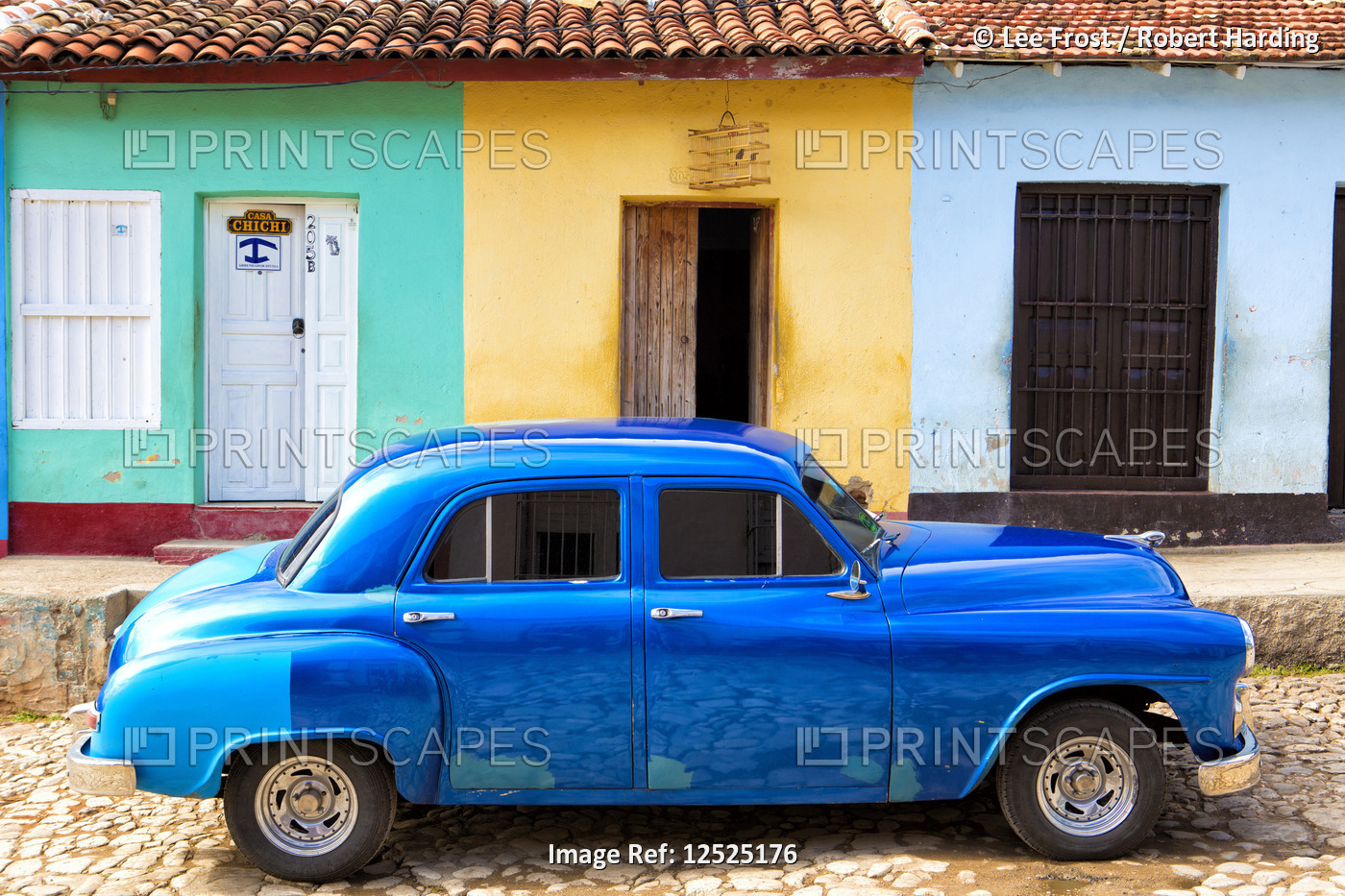 Bright blue vintage American car parked in front of colourful painted colonial houses, Trinidad, UNE
