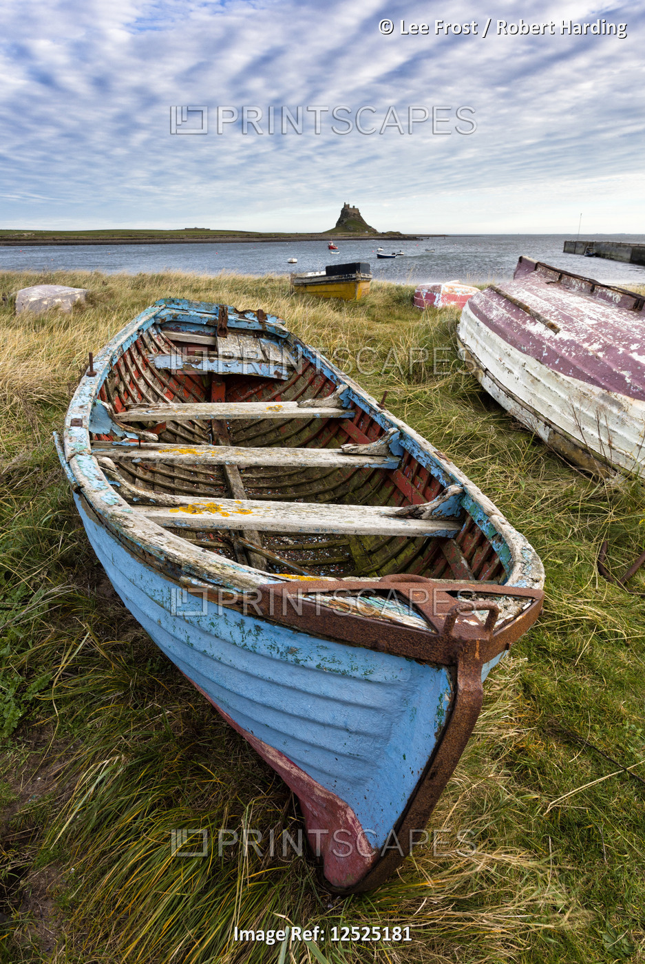 View towards Lindisfarne Castle with an old blue and red fishing boat in the foreground, Lindisfarne