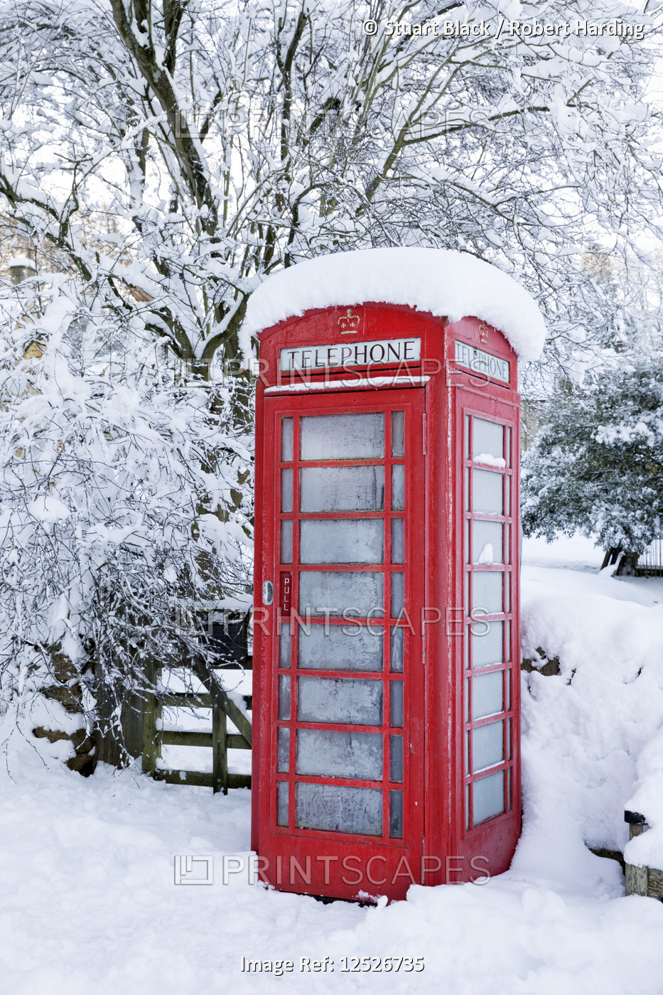 Traditional British red telephone box covered in winter snow, Snowshill, Cotswolds, Gloucestershire,