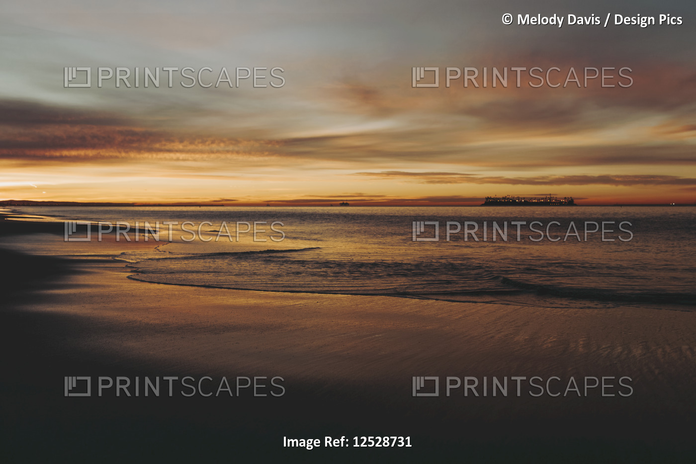Sunset washes gold and orange over the ocean and beach; Long Beach, California, ...