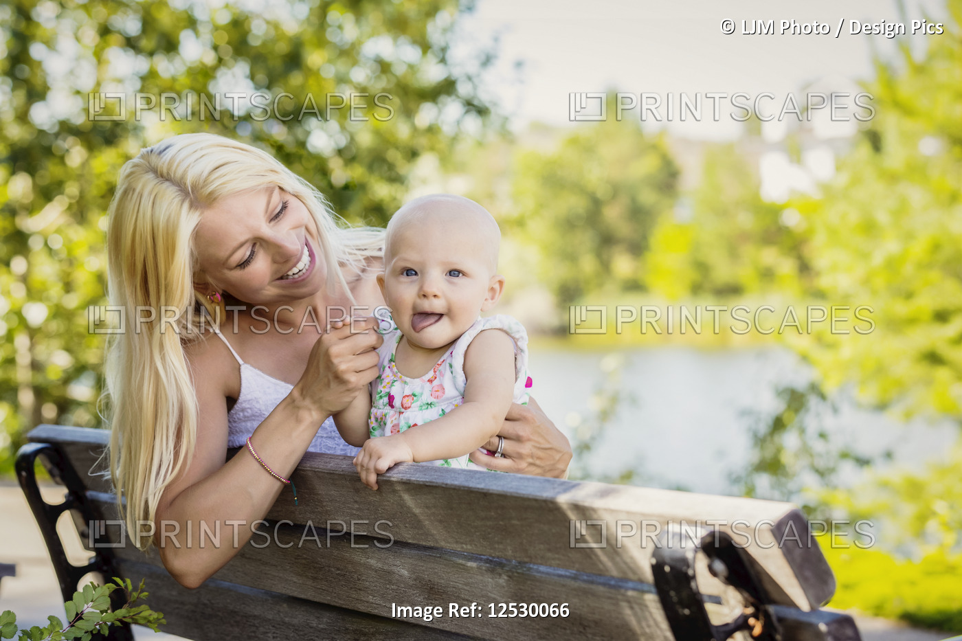 A young mother spending quality time with her baby daughter and sitting on a ...