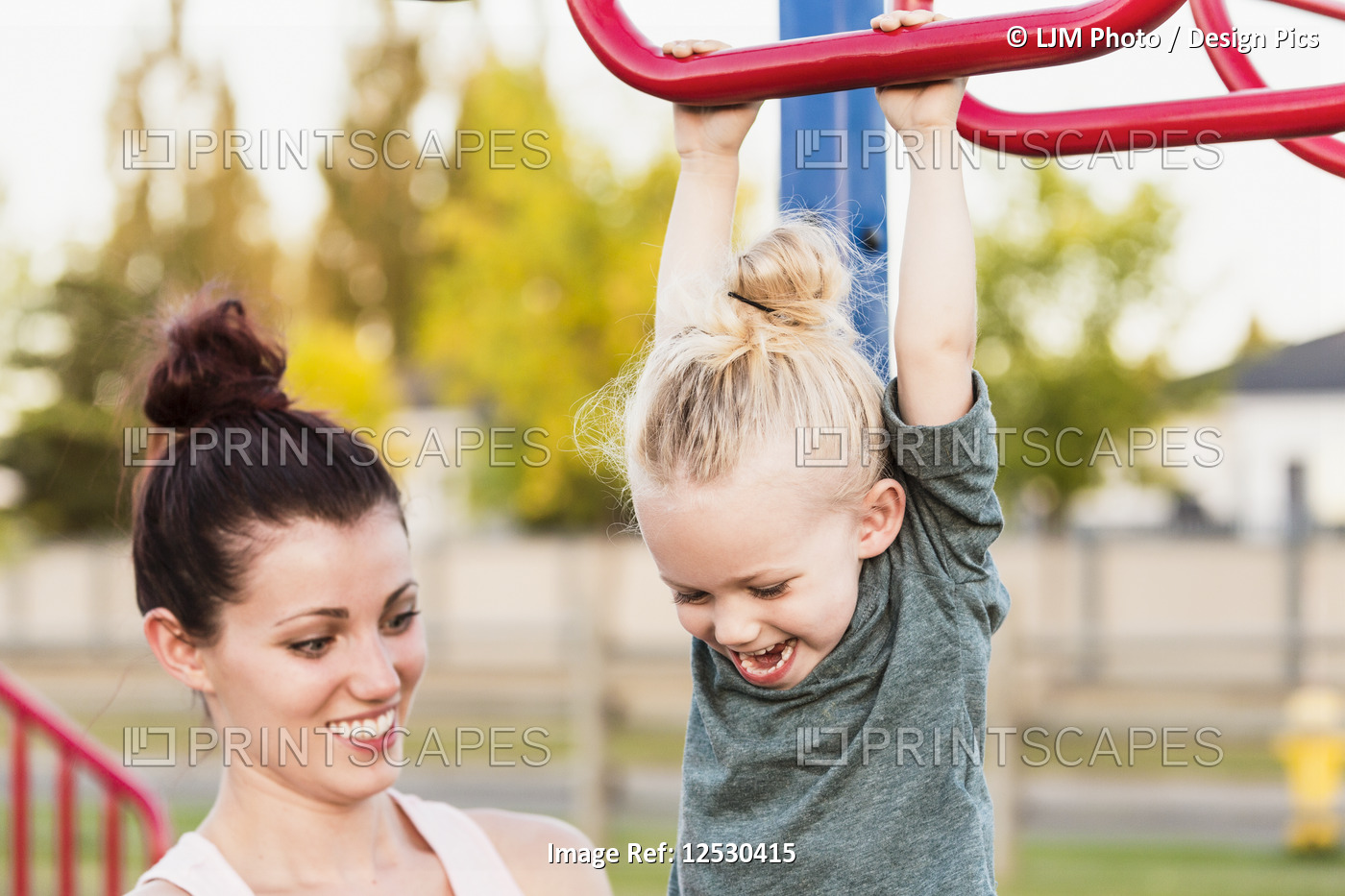 Young girl with blonde hair playing in in a playground on a warm fall day while ...