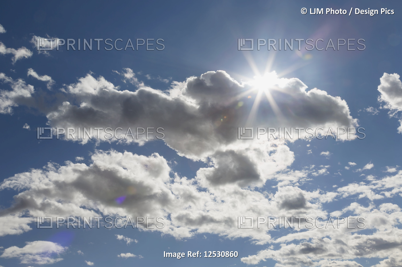 Cumulus clouds in a blue sky with sunlight bursting from behind; Edmonton, ...