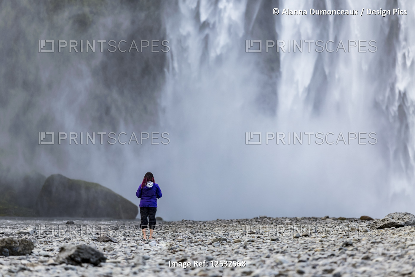 A female tourist looks towards the wall of water from Iceland's famous ...