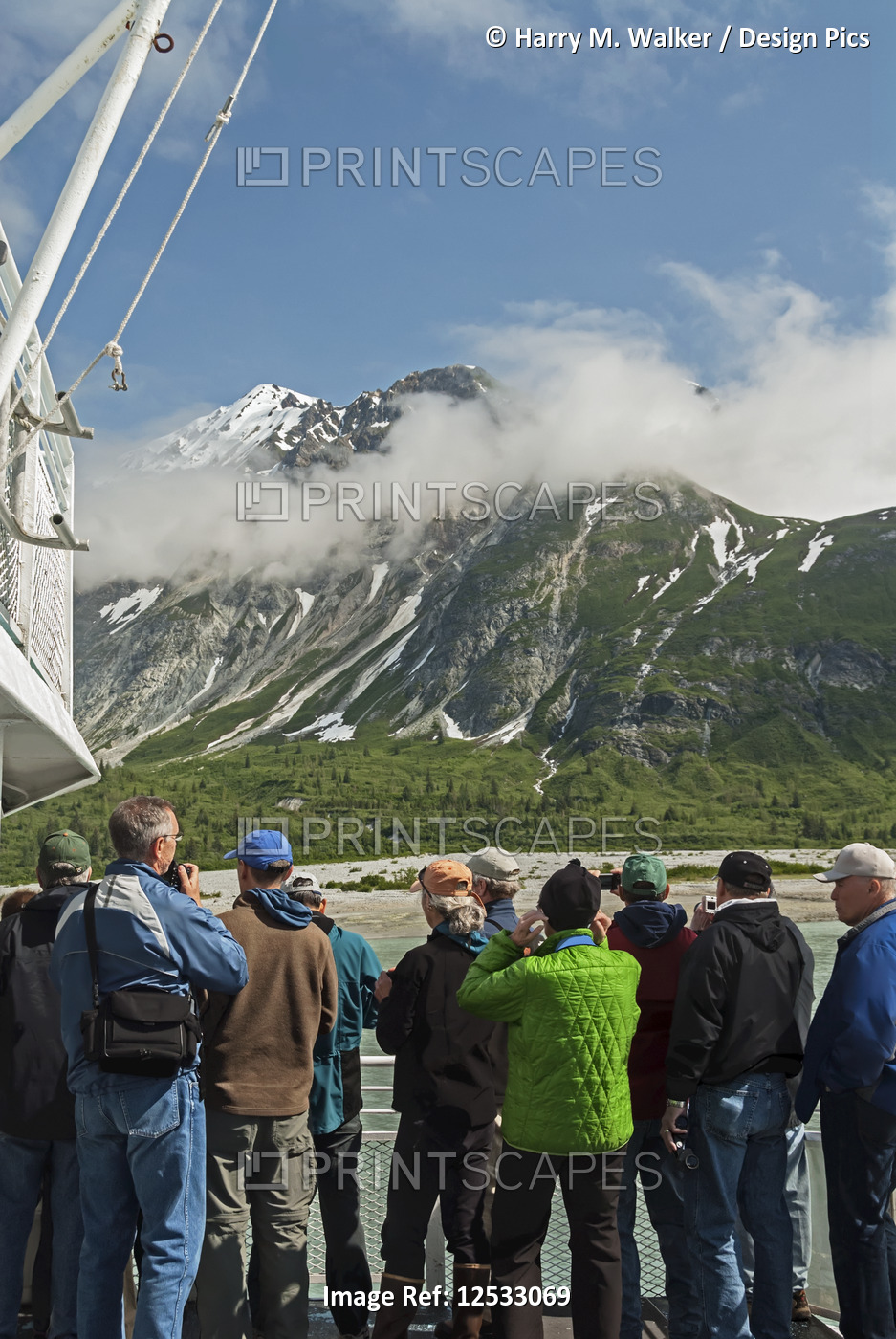 Tourists view scenery from the deck of day tour boat Baranof Wind of mountains ...