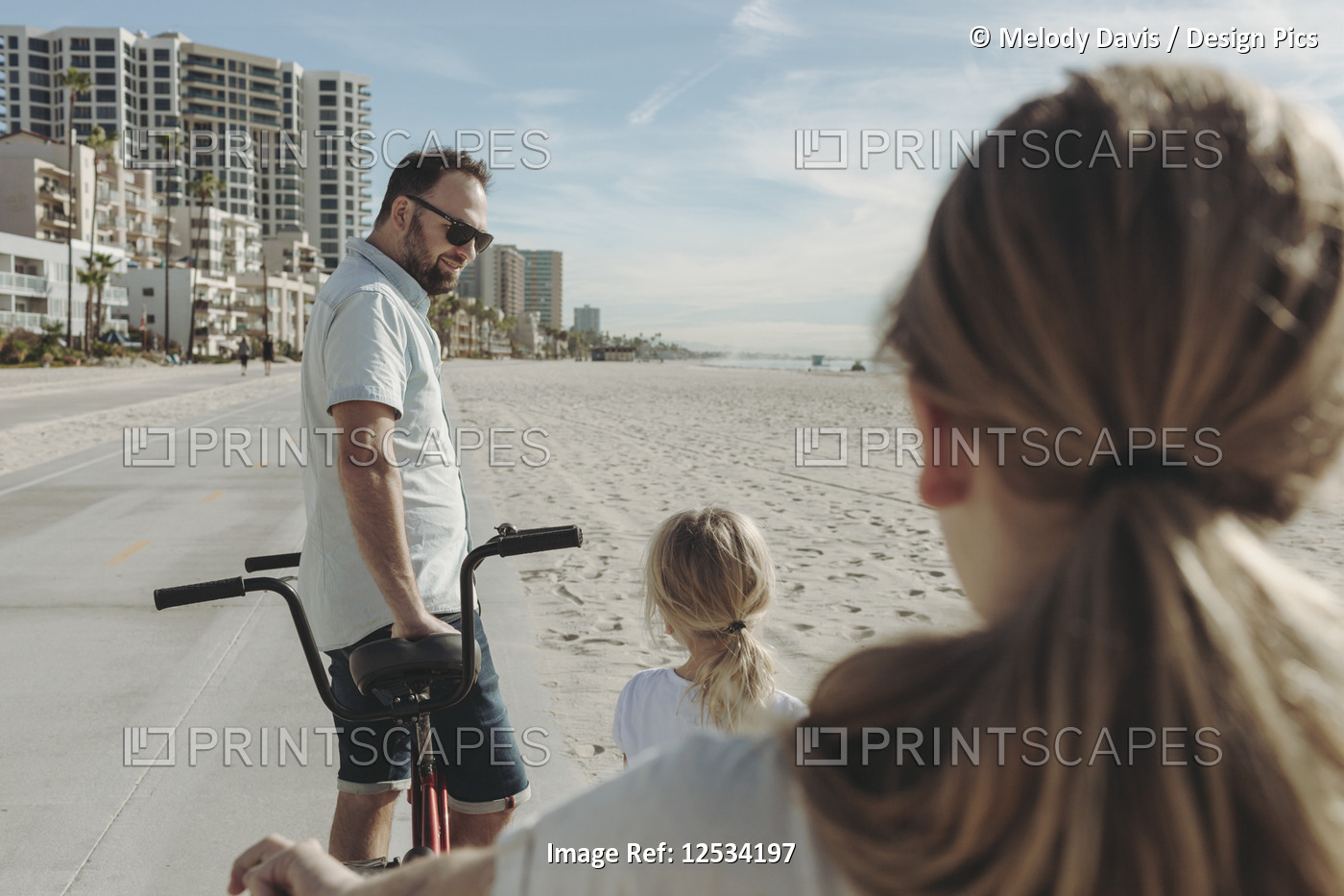 A father and daughters riding bikes at Long Beach; Los Angeles, California, ...