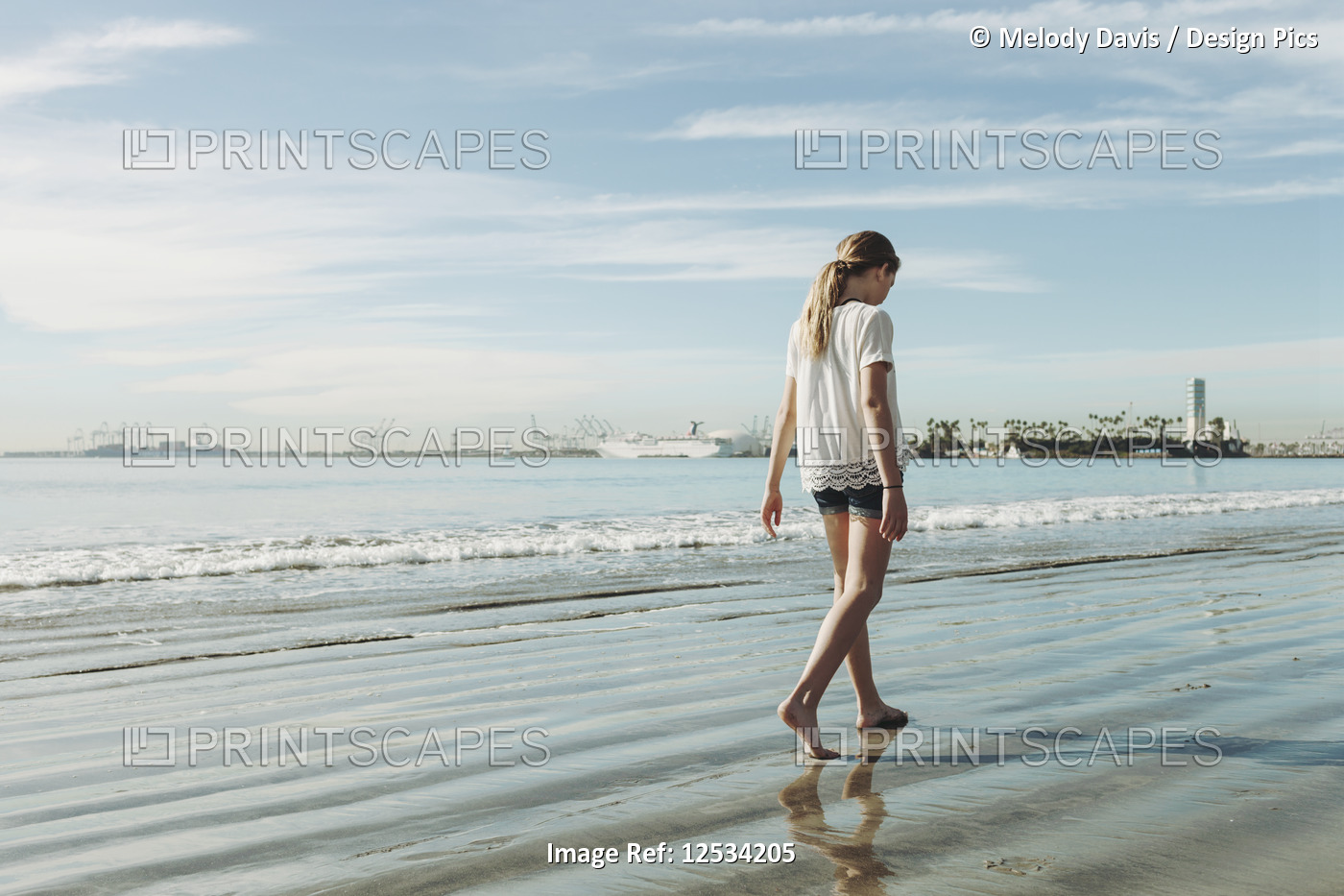 A girl walking on the beach on the wet sand; Long Beach, California, United ...