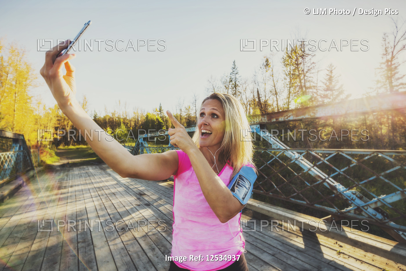 A woman wearing active wear and an arm band for her cell phone stands on a ...