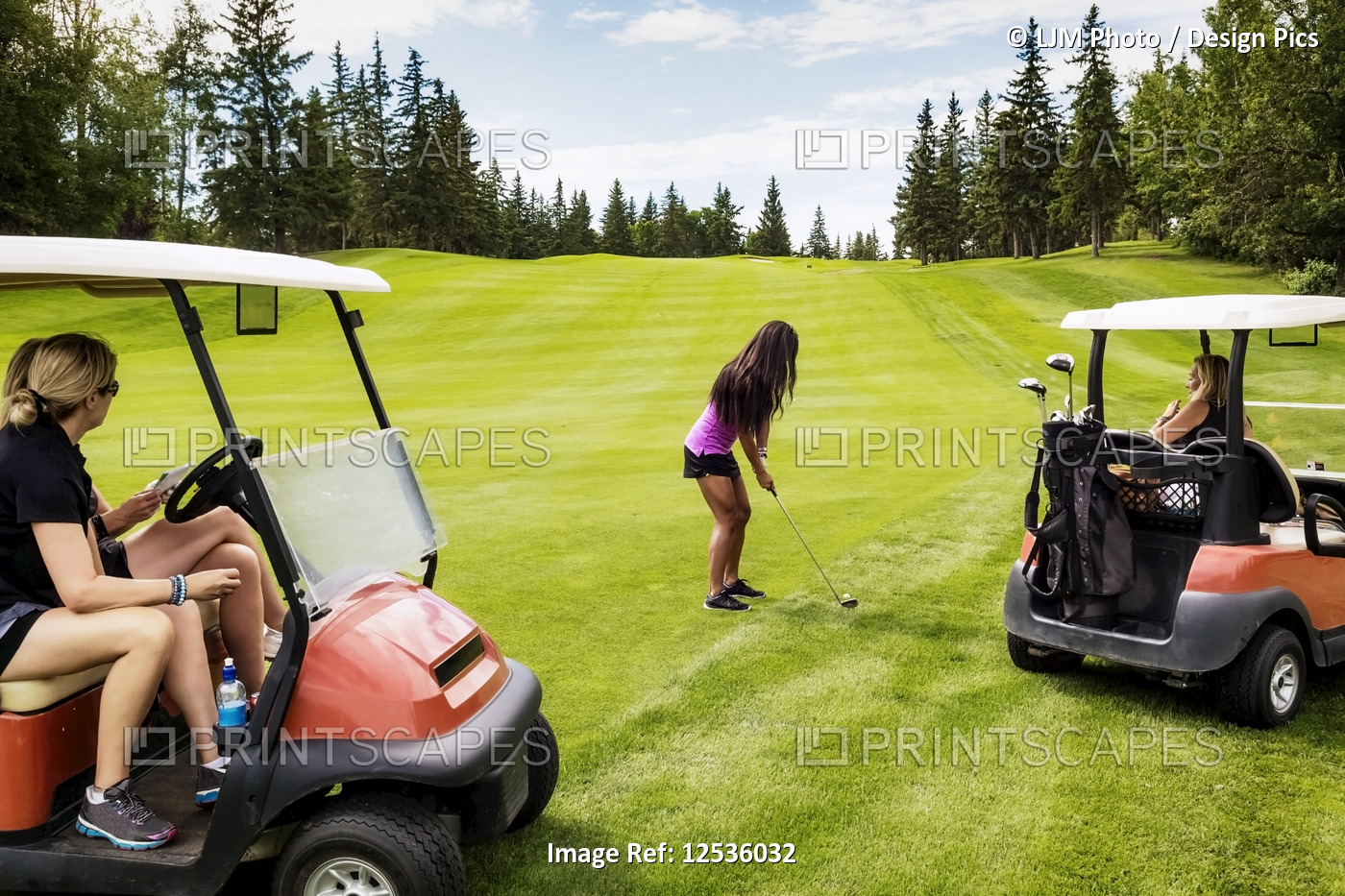 A group of female golfers watching from their golf carts while their teammate ...
