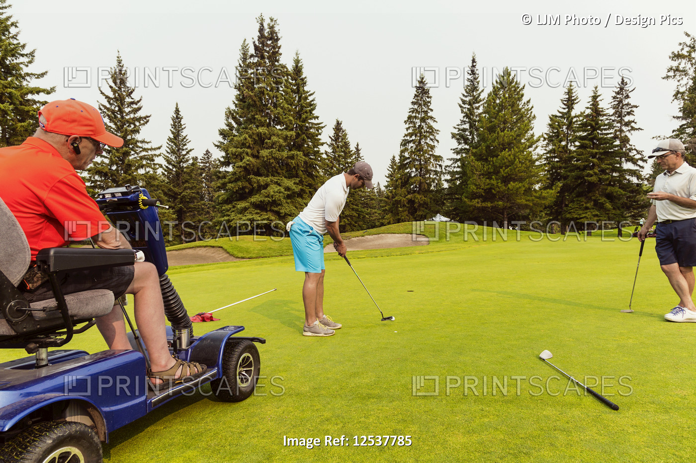 Two able bodied golfers team up with a disabled golfer using a specialized ...