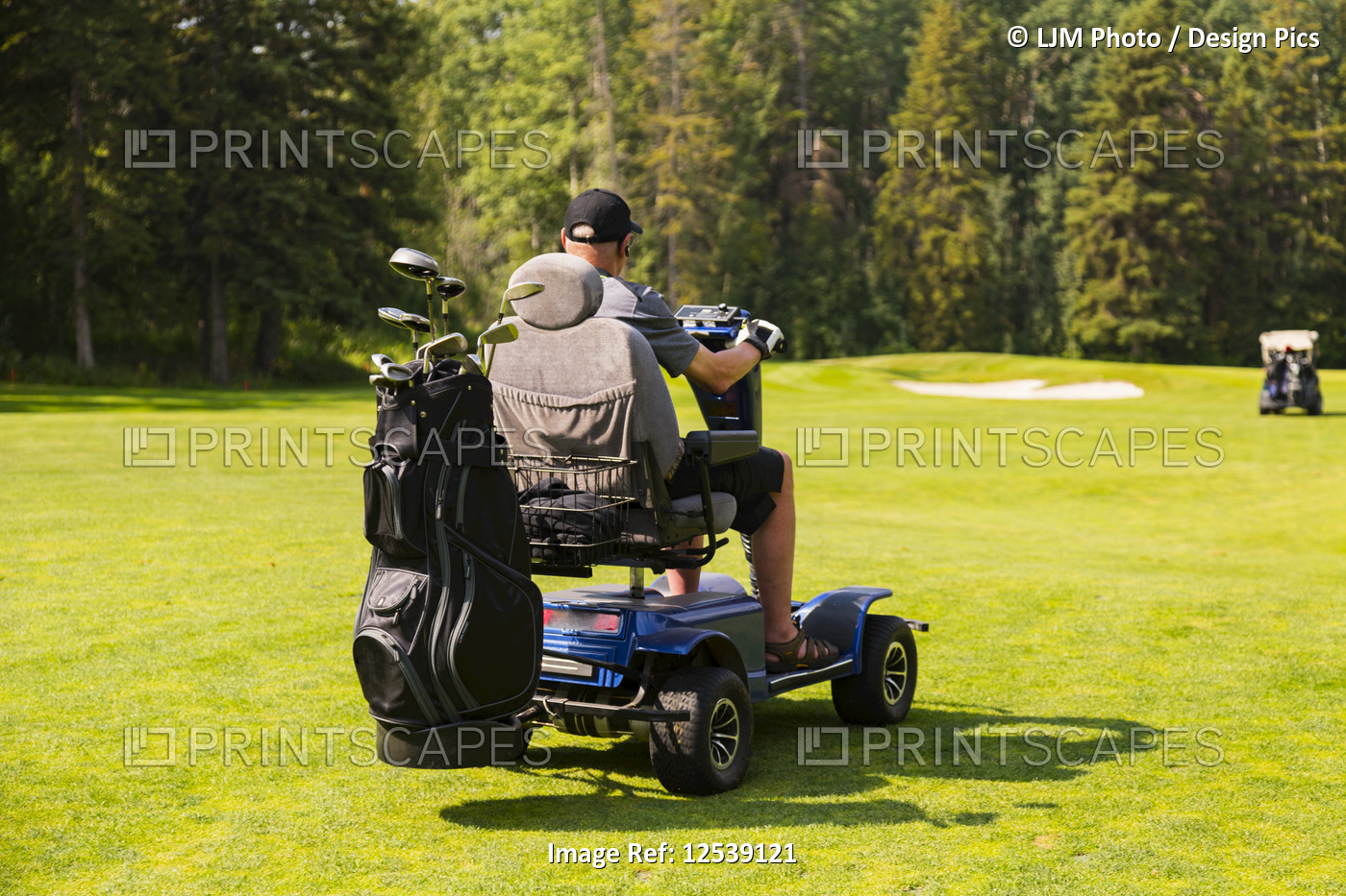 A physically disabled golfer driving a specialized golf wheelchair between ...