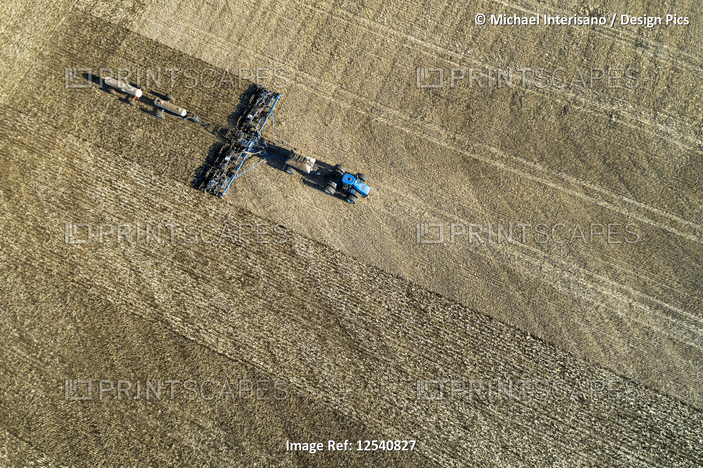 Aerial view of a tractor pulling an air seeder, seeding a field; Acme, Alberta, ...