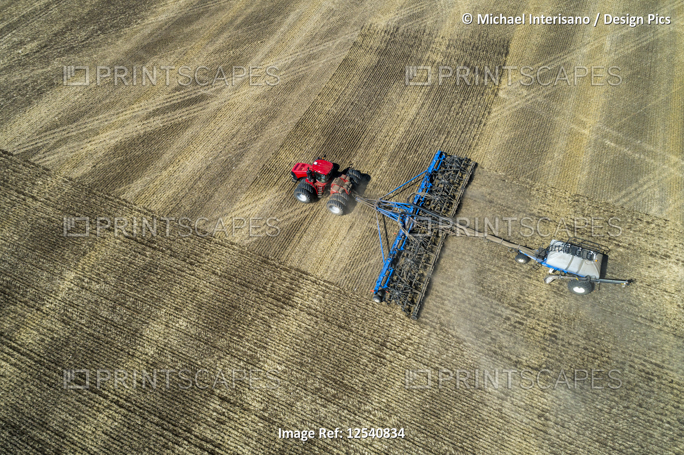 Aerial view of a tractor pulling an air seeder, seeding a field, West of High ...