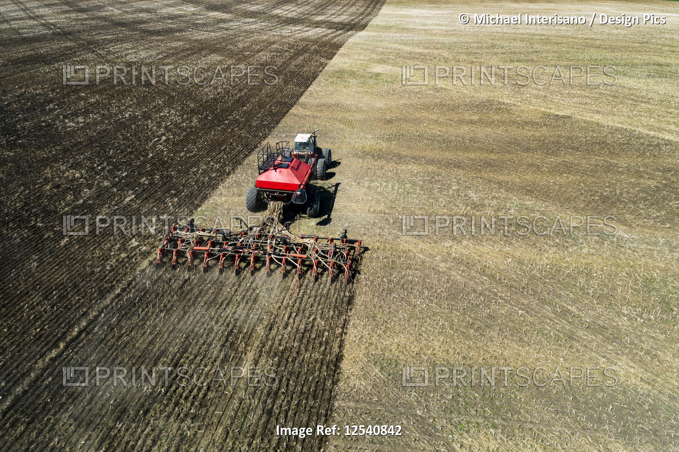 Aerial view of a tractor pulling an air seeder, seeding a field, West of High ...
