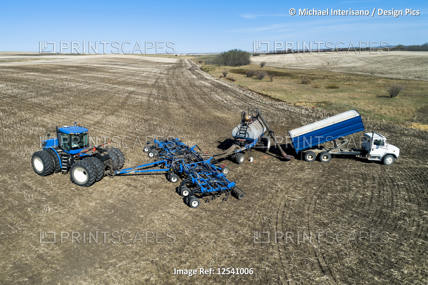 Aerial view of farmer filling an air seeder hopper with a truck in a field with ...