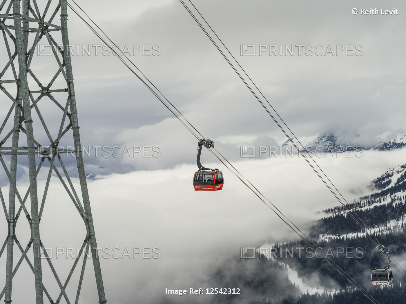 Red gondola lift on the cables above the mountains and clouds; Whistler, ...