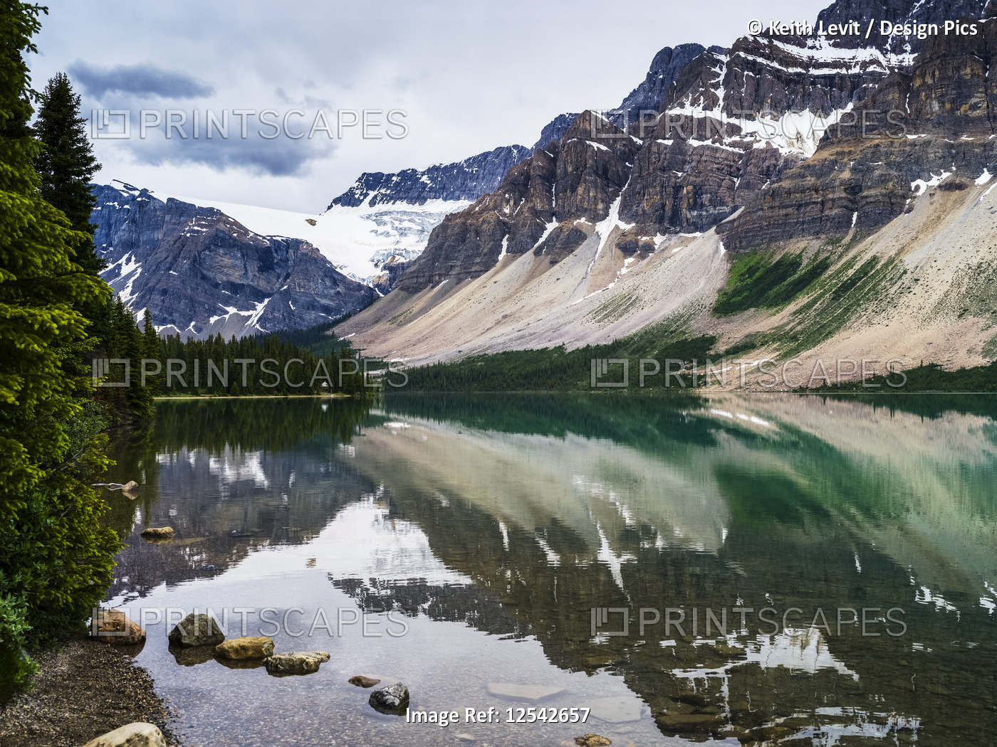 Rugged Canadian Rocky Mountains and glaciers reflected in a tranquil lake, ...