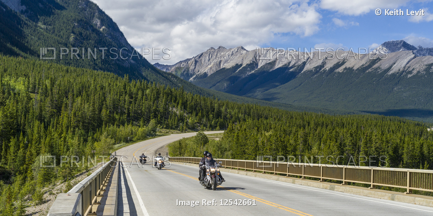 Motorcyclists travel a road through the rugged Canadian Rocky Mountains in ...