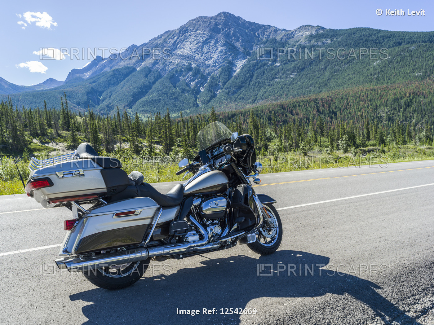 A motorcycle parked on the side of the road with view of the Rocky Mountains, ...