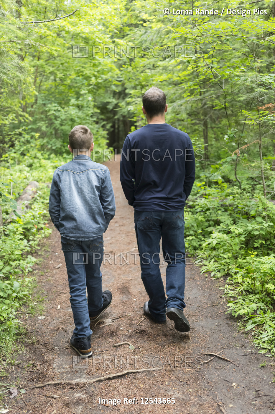 Father and son walking together on a trail; Salmon Arm, British Columbia, Canada