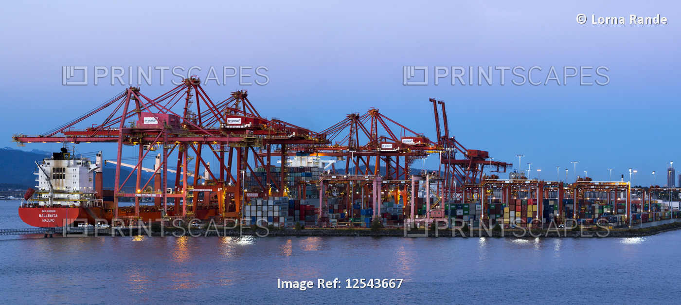Ships and shipping containers along a waterfront at dusk; Vancouver, British ...