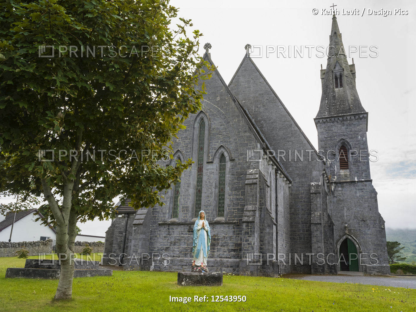 Stone church with bell tower and statue of praying woman in front; County ...