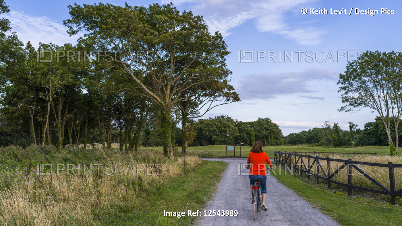 A woman rides her bike down a road at Gleno Abbey Hotel and Golf Course; County ...