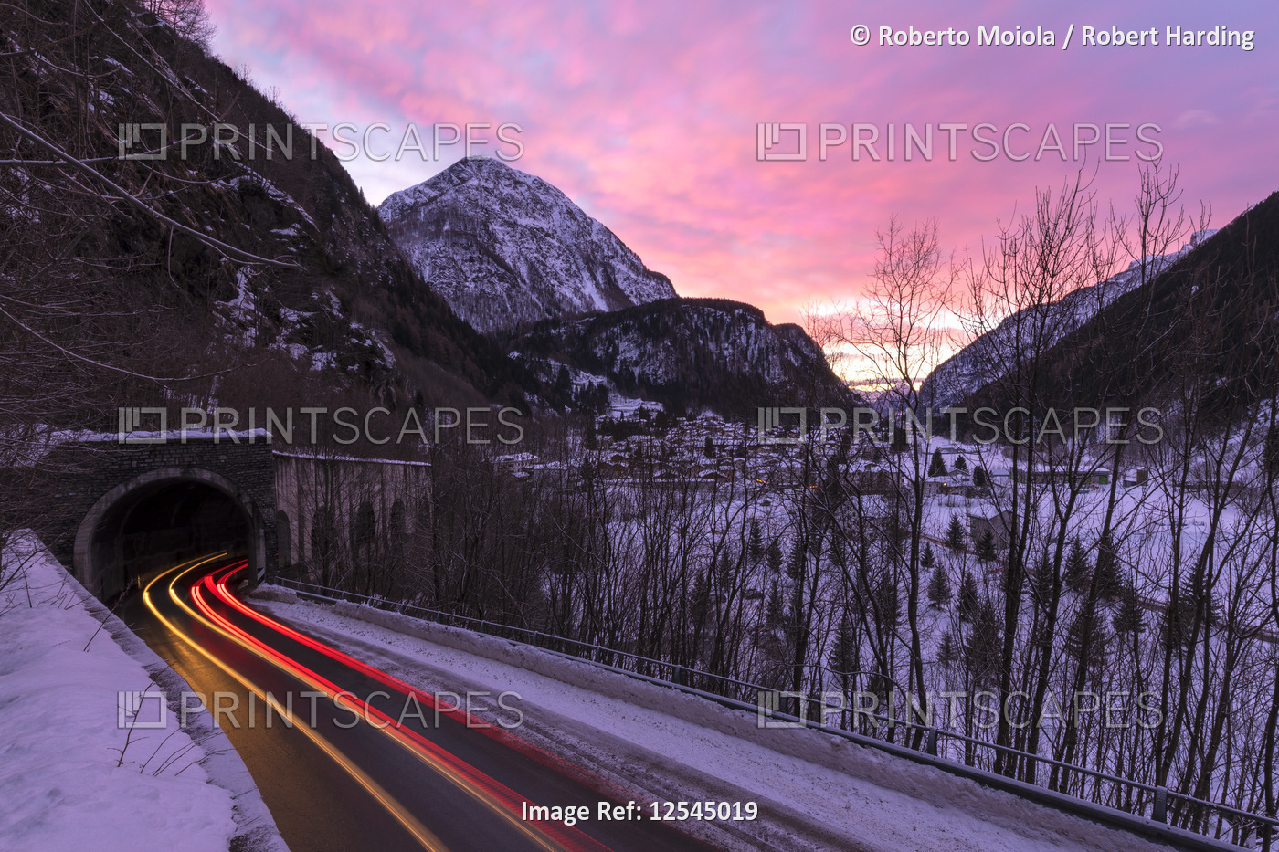 Car trails lights on the icy road at dawn, Campodolcino, Spluga valley, Sondrio province, Valtellina