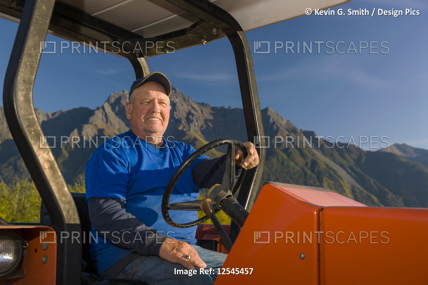 A farmer wearing a blue shirt sits on an old red tractor in an open field, ...