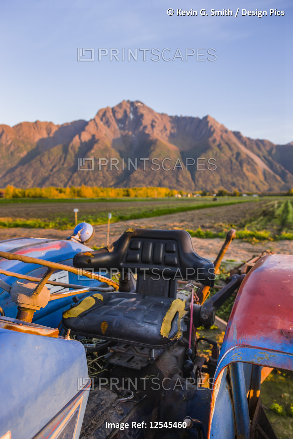 A blue tractor sits below Pioneer Peak illuminated by sunset, South-central ...