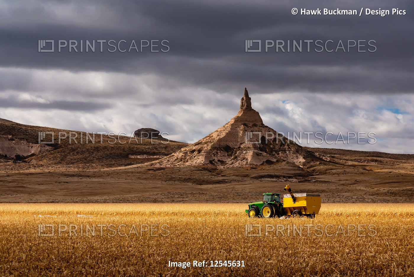 Tractor with combine on farm field and chimney rock, Scotts Bluff National ...