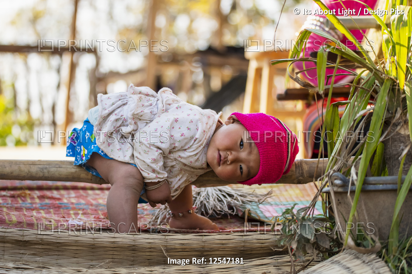Adorable Thai baby posing for the camera while sitting and laying her head on ...