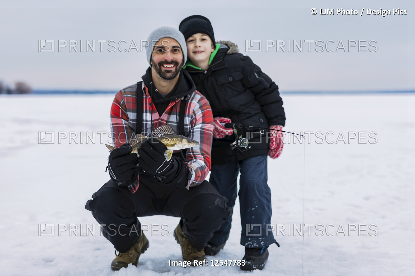 Father and young son showing off their catch of a walleye before releasing it ...
