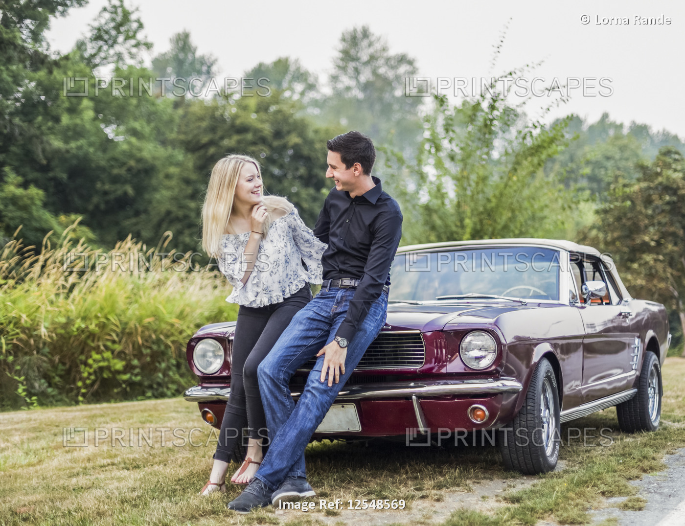 A young couple standing with a vintage sports car; Bothell, Washington, United ...