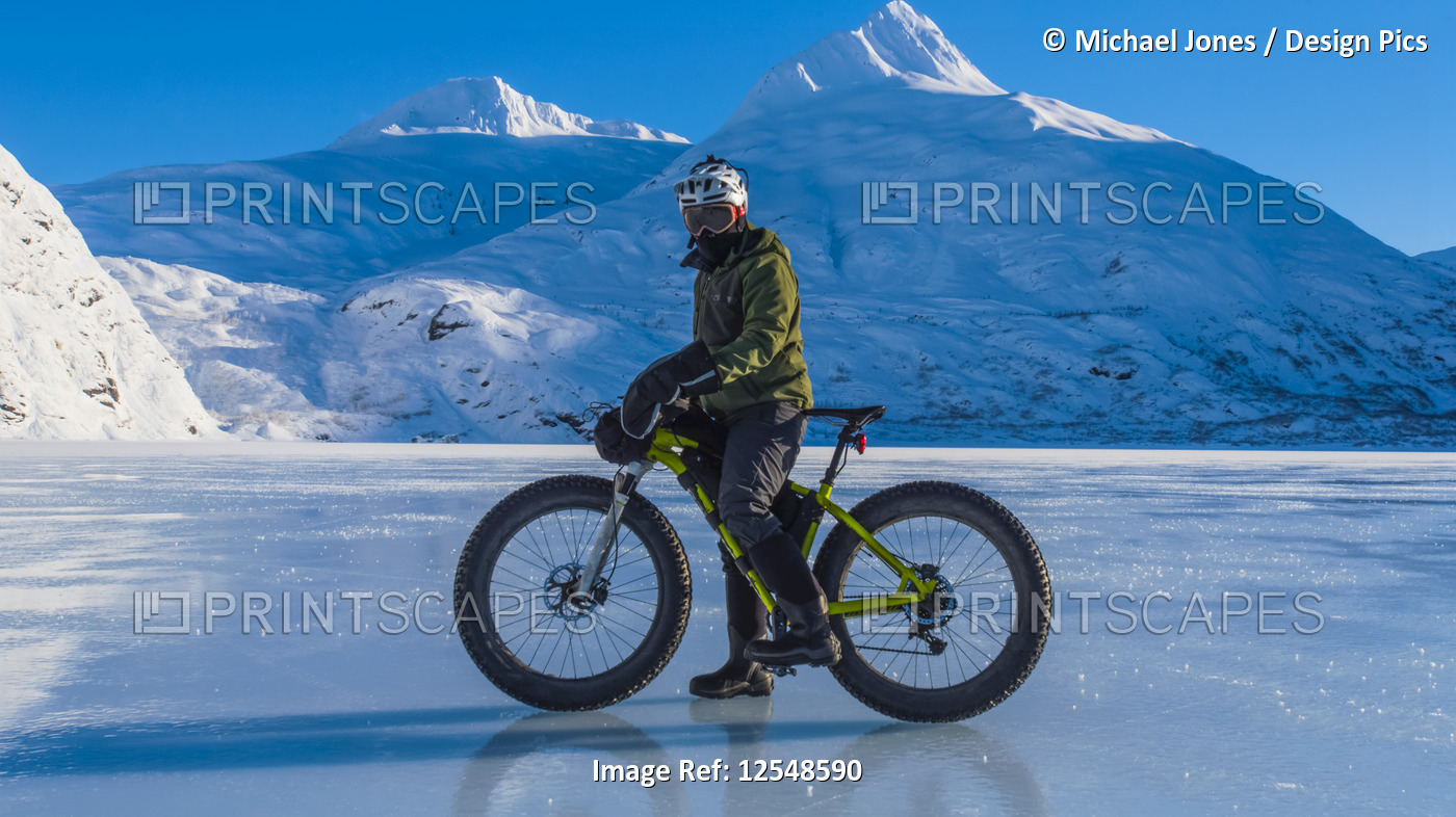 A man riding his fatbike across frozen Portage Lake in mid-winter in ...