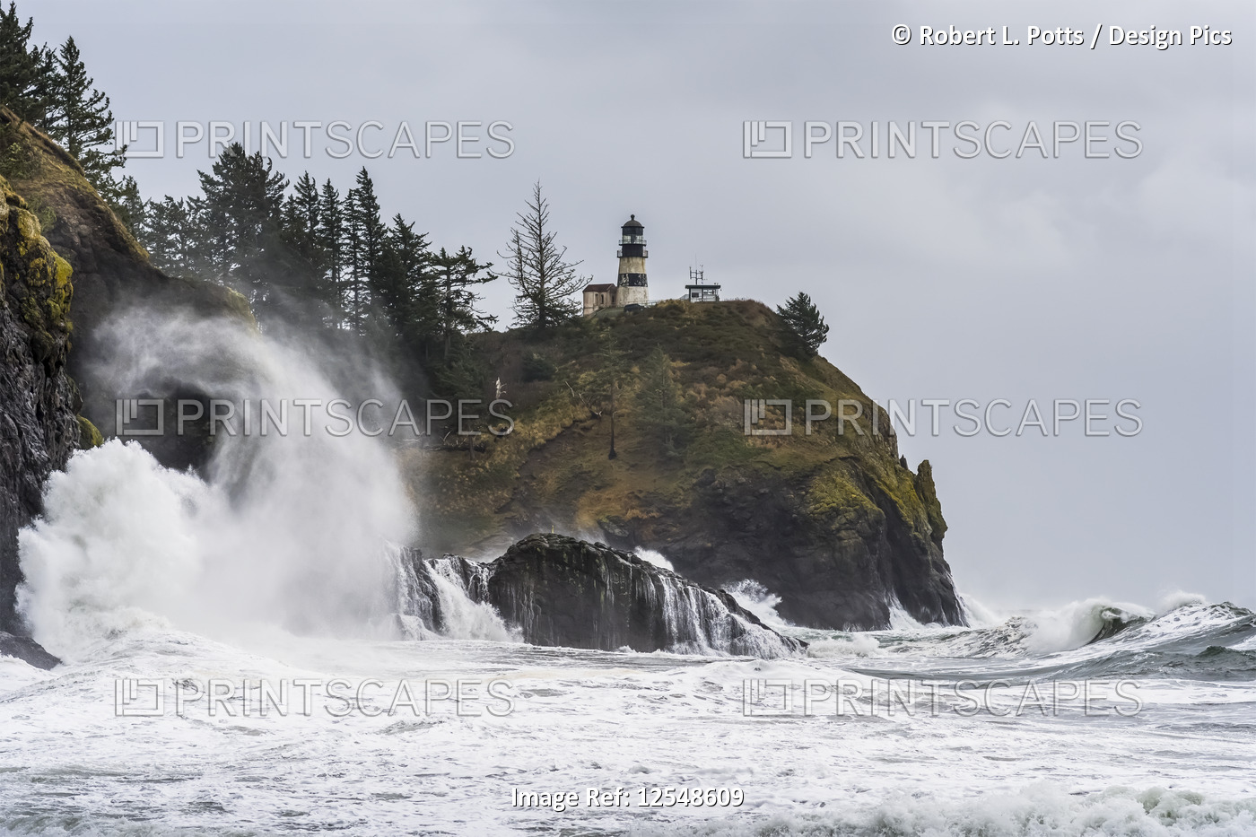 Surf fills the air with salt spray at Cape Disappointment with a lighthouse up ...