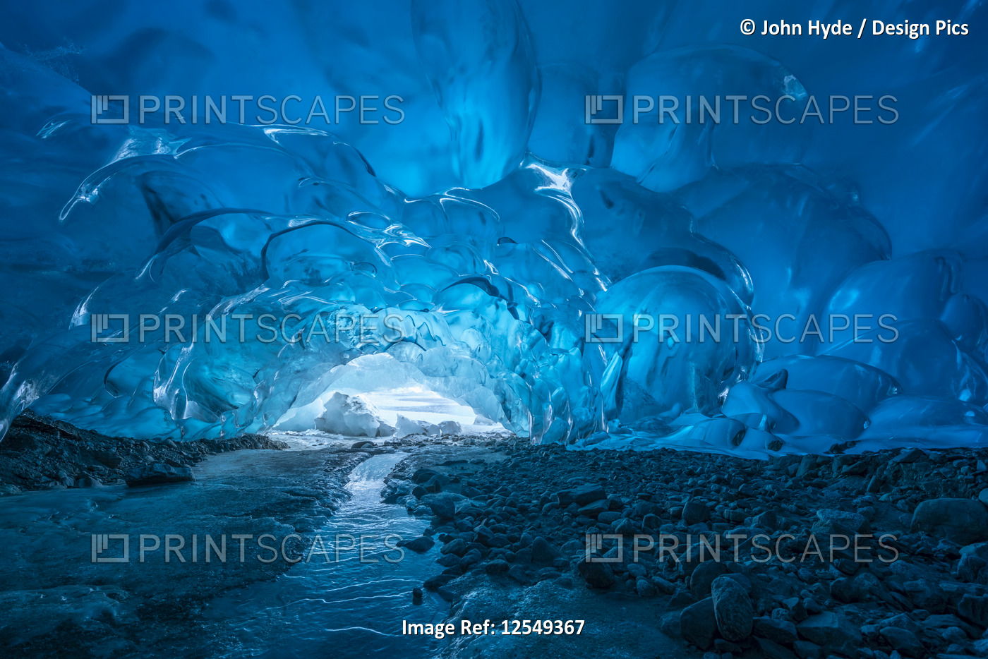 Blue glacial ice is exposed inside an ice cave at the terminus of Mendenhall ...