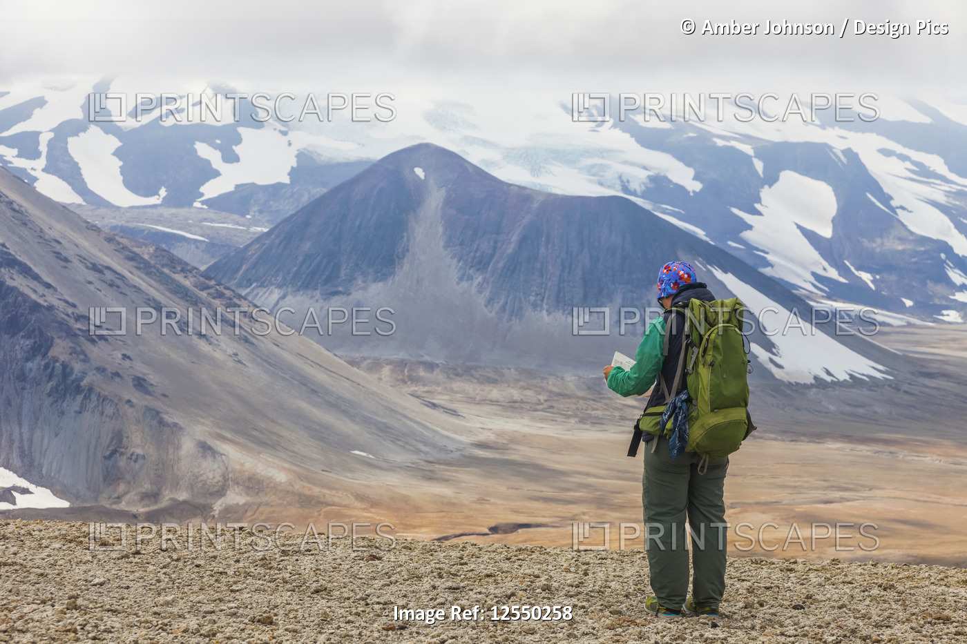 Woman backpacking and checking map with Mount Katmai in background, Valley of ...