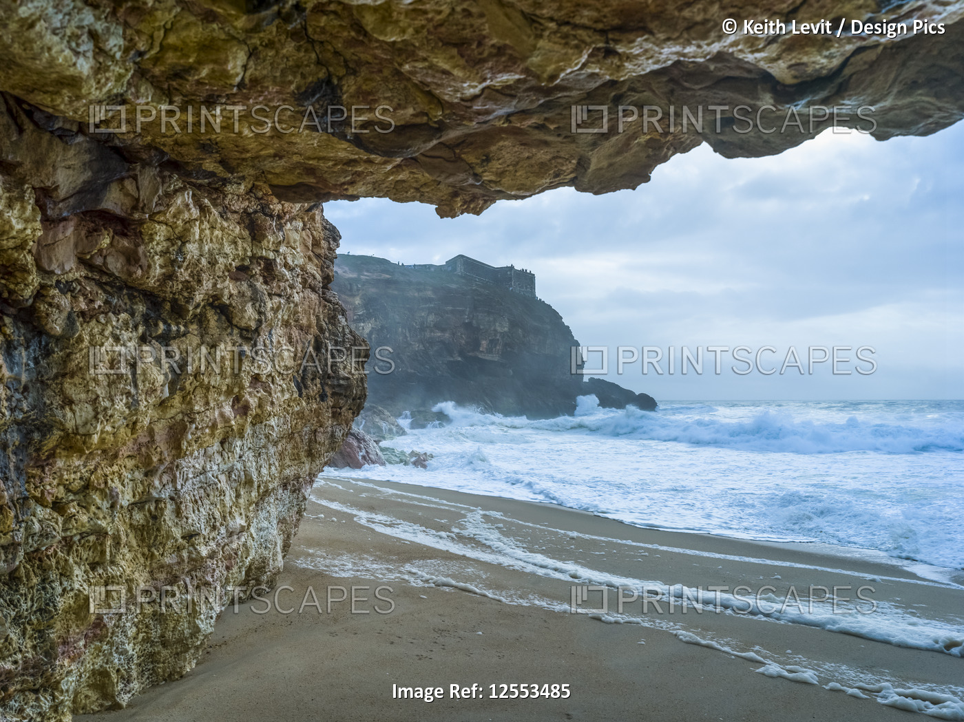 Nazare beach with rugged cliffs and rough waves; Nazare, Leiria District, ...