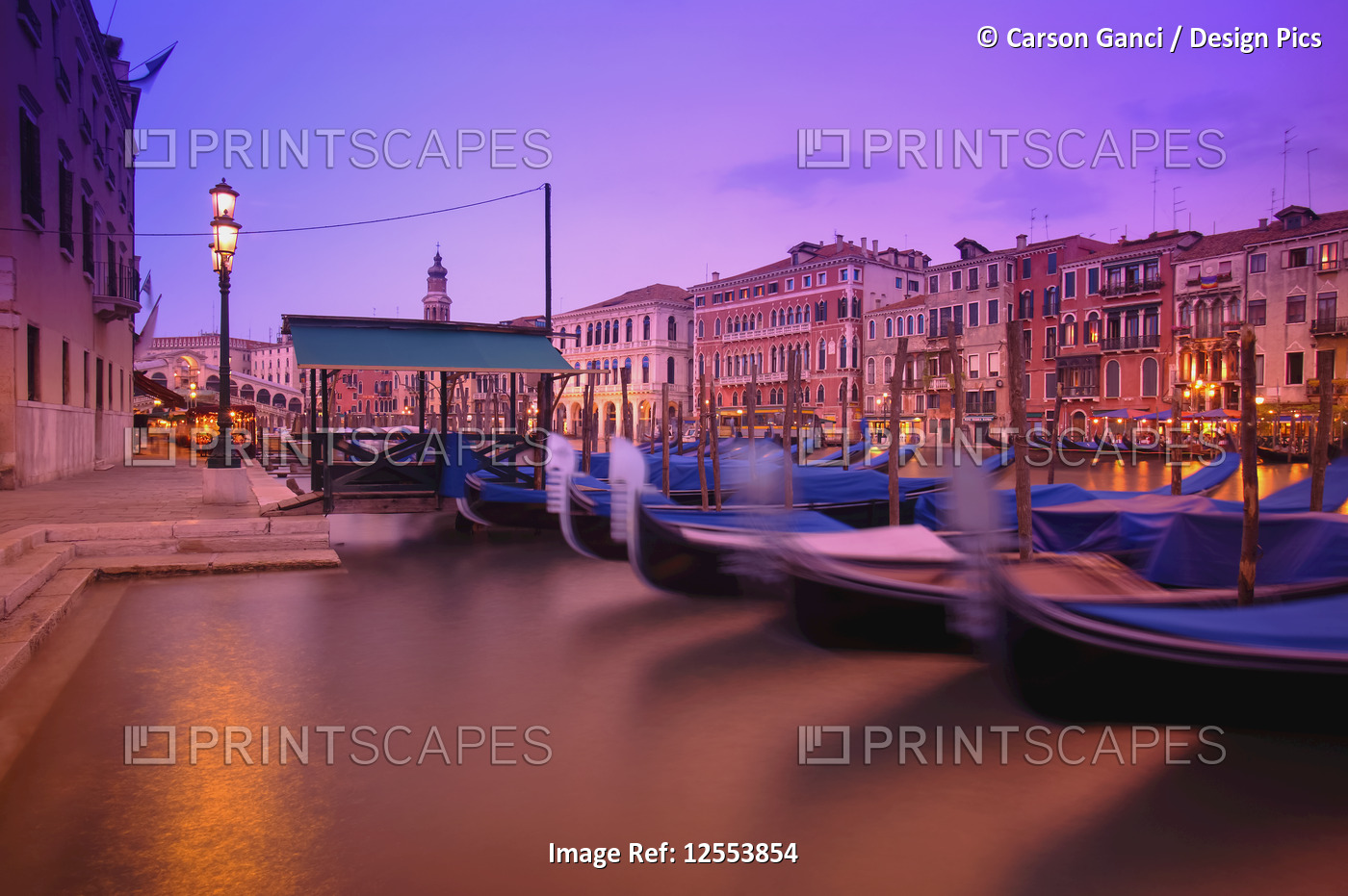Gondolas moored along the shoreline of the Grand Canal during a vibrant sunset; ...
