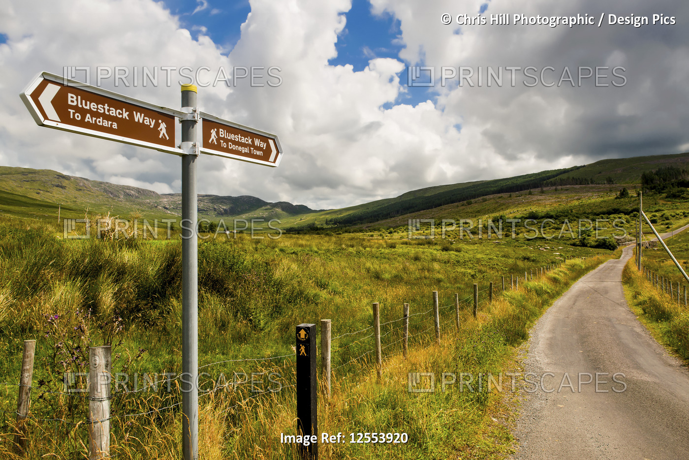 A sign for hiking trails, Bluestack Way, and a road leading through a hilly ...