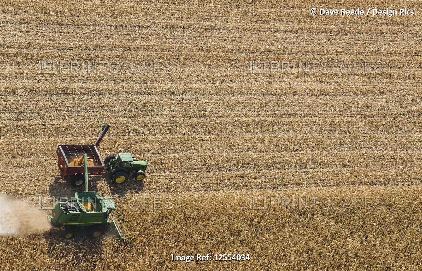 A combine harvester unloads soybeans into a grain wagon on the go during the ...