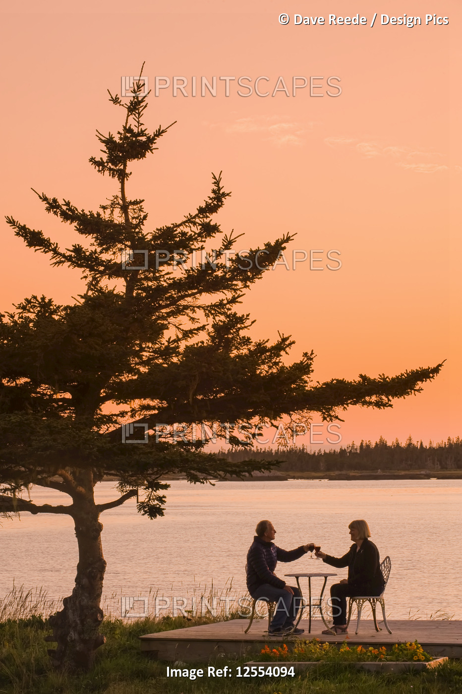 Couple relaxing along the Atlantic coast at sunset, Bay of Fundy; Blanche, Nova ...