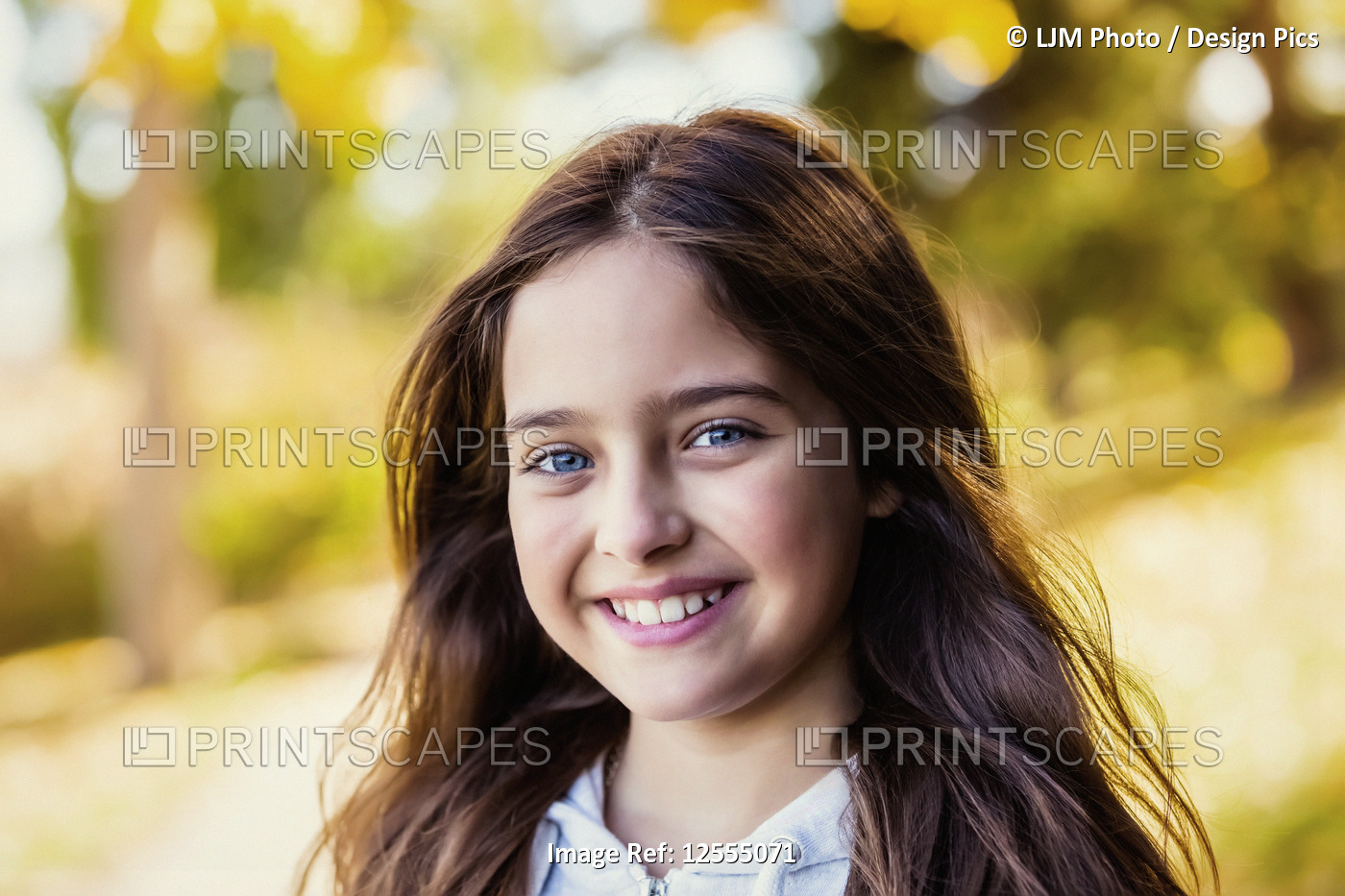 A young girl posing for the camera in a city park on a warm autumn day; ...